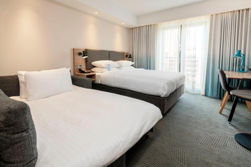 a hotel room with two beds and a desk at Holiday Inn London Brentford Lock by IHG in Brentford