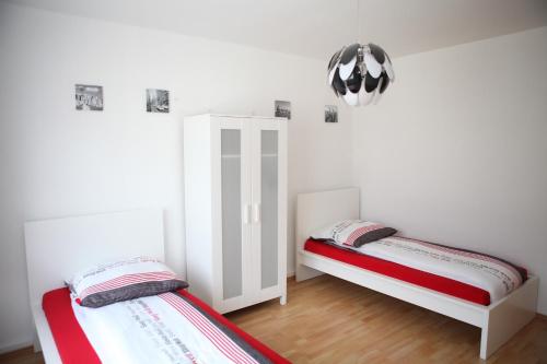 two beds in a room with white walls and wood floors at Apartment Am Ring in Bochum