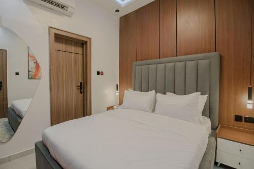 a bedroom with a large white bed with a wooden headboard at One90 Apartment in Lagos
