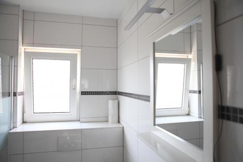 a white bathroom with two windows and a mirror at Apartment Am Ring in Bochum