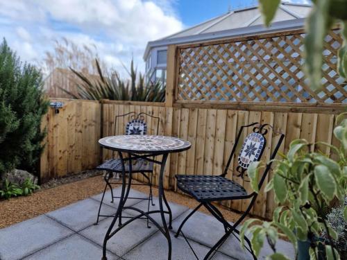 a patio with two chairs and a table and a fence at The Little Baytree in Worle