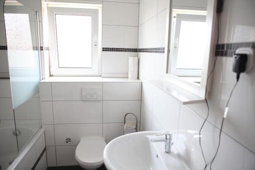 a bathroom with a sink and a toilet and two windows at Apartment Am Ring in Bochum