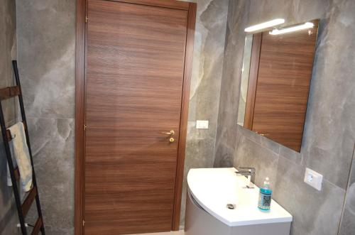 a bathroom with a sink and a wooden door at Monolocale Casa Palma in Nardò