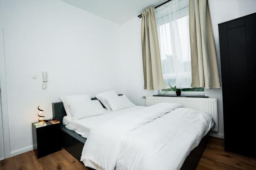 a bedroom with a bed with white sheets and a window at Chambre R1 avec salle de bain partagée près de l'hôpital de la Citadelle à Liège in Liège