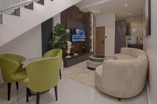 a living room with green chairs and a tv at One90 Apartment in Lagos