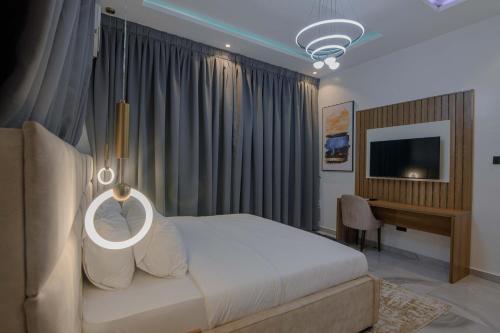 a bedroom with a bed and a desk and a television at One90 Apartment in Lagos