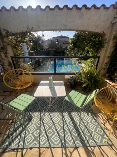 a patio with a table and chairs and a swimming pool at La villa des oliviers in Sorède