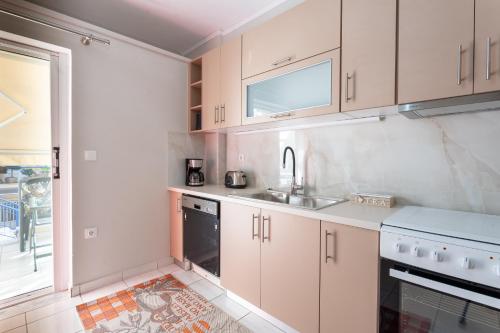 a kitchen with white cabinets and a sink at Comfortable 3-Bedroom Maisonette Near the Sea in Mytilini