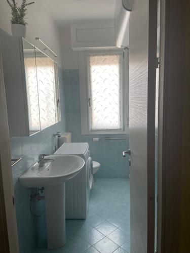 a bathroom with a sink and a toilet and a window at Appartamento al Condominio Concordia in Grado