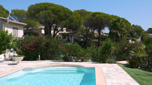 - une piscine dans une cour ornée d'arbres et de fleurs dans l'établissement Grand Appartement dans Maison avec Piscine Privée, à Fréjus