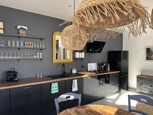 une cuisine avec des armoires noires et un comptoir avec une table dans l'établissement Villas Ambiance 21 Elégance Méditerranéenne à Portiragnes, entre Terre et Mer Villa Helma, à Portiragnes