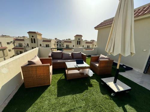 a patio with a couch and chairs and an umbrella at Lasirena north coast Chalet With Roof , 3 rooms in Zāwiyat ‘Abd al Mun‘im