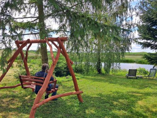a person sitting on a wooden swing in a park at Agroturystyka Nasza Bajka in Pieniężno