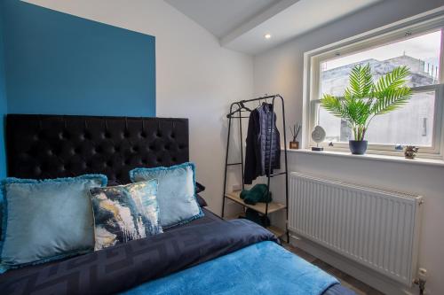 a bedroom with a bed with blue pillows and a window at The Lanes Diamond - Rose Platinum Properties in Brighton & Hove