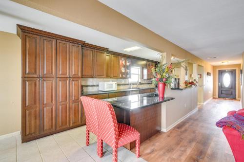a kitchen with wooden cabinets and a red chair at Near Ocean Home with Deck and Grill in Surfside Beach in Surfside Beach