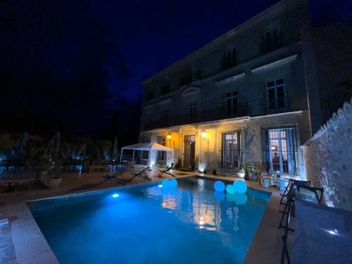 a large swimming pool in front of a building at night at Demeure Sainte Clotilde, événementiel et chambres d'hôtes à Neffies in Néffiès