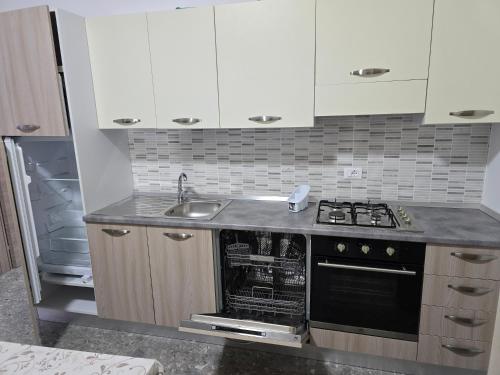 a kitchen with white cabinets and a stove and a sink at Da Massimo 1 in Marina di Schiavonea