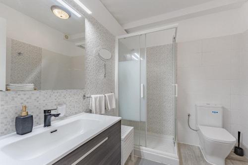 a white bathroom with a sink and a toilet at Primavera Tranquil Retreat 2-Bedroom Apartment with Balcony, Garden View & Fiber WiFi in Arona