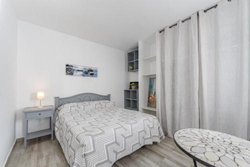 a white bedroom with a bed and a table at Primavera Tranquil Retreat 2-Bedroom Apartment with Balcony, Garden View & Fiber WiFi in Arona