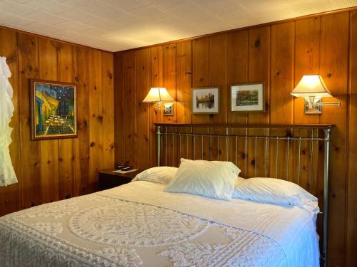 a bedroom with a bed with wooden walls and two lamps at Ludington Blue Spruce Inn in Ludington