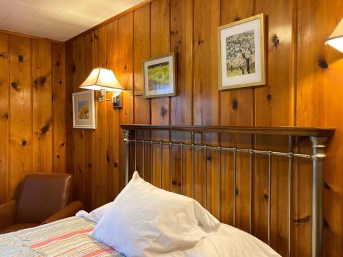 a bedroom with wooden walls and a bed and a lamp at Ludington Blue Spruce Inn in Ludington