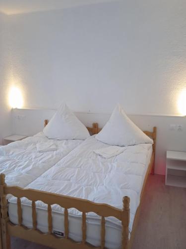 a bed with white sheets and pillows on it at Hotel Konty in Kąty Opolskie