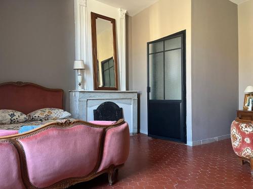 a bedroom with a couch and a fireplace and a mirror at Demeure Sainte Clotilde, événementiel et chambres d'hôtes à Neffies in Néffiès