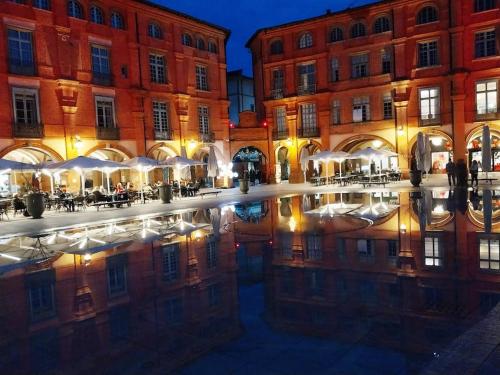 a building with a reflection in a pool of water at Logis Groly gîte avec spa en campagne proche Montauban in Genébrières