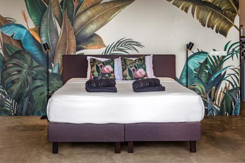 a bed in a room with a mural of plants at PM78 Boutique Apartments in Willemstad