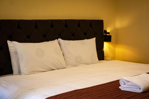 a bed with white pillows and a black headboard at Santuario Machupicchu in Machu Picchu