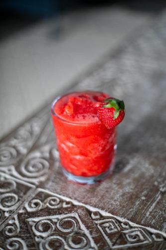a red drink with a strawberry in it on a table at Divinity Costa Rica All Inclusive Luxury Villa in Dominical