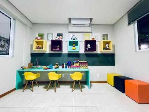 a play room with a table and two yellow chairs at Apto 6º andar, 200m praia, 15min Beto Carrero, 2 quartos, sacada com churrasqueira in Piçarras