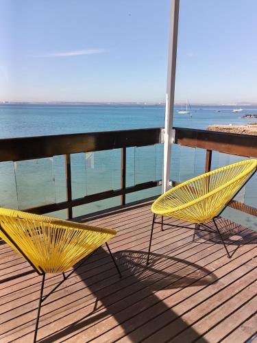 two yellow chairs sitting on a deck overlooking the ocean at Hoedjiesbaai Hotel in Saldanha