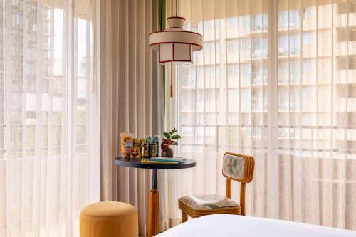 a bedroom with a bed and a table and a window at Wayfinder Waikiki - Voted Top 10 Best Hotels in Hawaii! in Honolulu