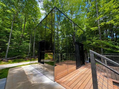 a glass house with two doors on a wooden deck at Couples Mirror Cabin- Reflections at Valley Bear Farms Resort in Balsam Grove