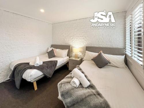 a bedroom with two beds and a window at Bundarra One in Jindabyne