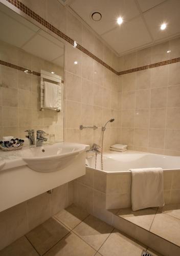 a bathroom with a tub and a sink and a bath tub at Hotel Pacific in Ostend