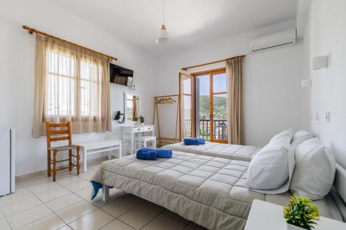 a bedroom with two beds and a table and a desk at White Lily in Skopelos Town