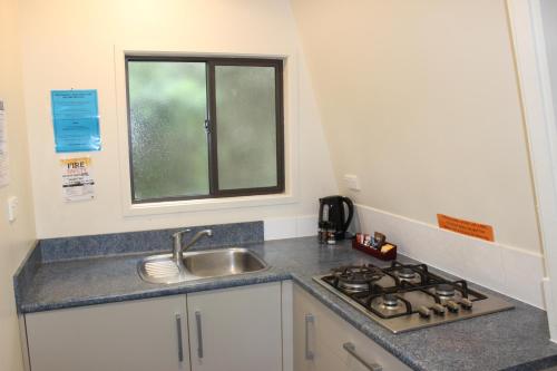 a kitchen with a sink and a stove and a window at Whatuwhiwhi TOP 10 Holiday Park in Tokerau Beach