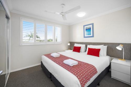 a bedroom with a large bed with red pillows at 3 Bedroom Apartment with Lift in Caloundra