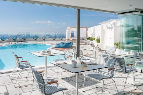 a patio with tables and chairs next to a pool at Caldera's Dolphin Suites in Megalokhori