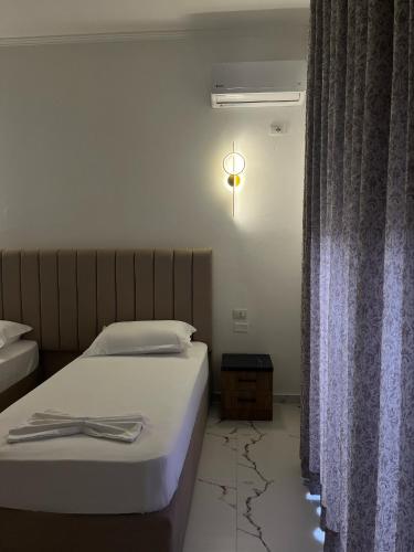 a hotel room with two beds and a window at Xhefri's Apartments in Vlorë