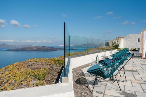 a green bench sitting on a patio overlooking the water at Caldera's Dolphin Suites in Megalokhori