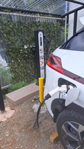 a white car is plugged into a electric car charger at HOTEL, VILLAS y GLAMPINGS MYA -PUERTO VIEJO, Limon, CR in Puerto Viejo