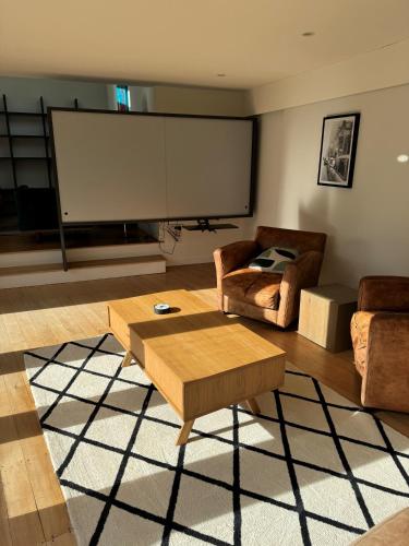 a living room with a large screen in the wall at Luxurious Kiwiana Raumati Beachfront Home in Paraparaumu