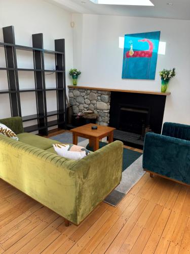 a living room with a green couch and a fireplace at Luxurious Kiwiana Raumati Beachfront Home in Paraparaumu