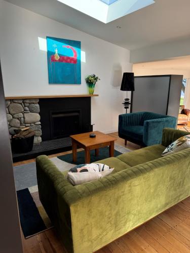 a living room with a green couch and a fireplace at Luxurious Kiwiana Raumati Beachfront Home in Paraparaumu