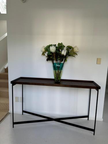 a vase of flowers sitting on a table at Luxurious Kiwiana Raumati Beachfront Home in Paraparaumu