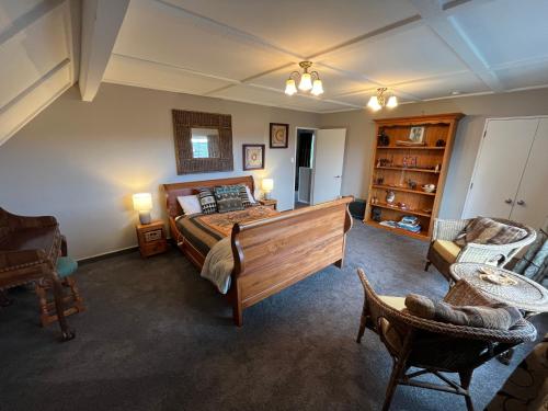 a bedroom with a large bed and a living room at Tudor Manor Bed & Breakfast in Paraparaumu Beach