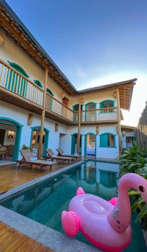 a pool with a pink inflatable swan in front of a house at Flô Casa Hotel in Trancoso